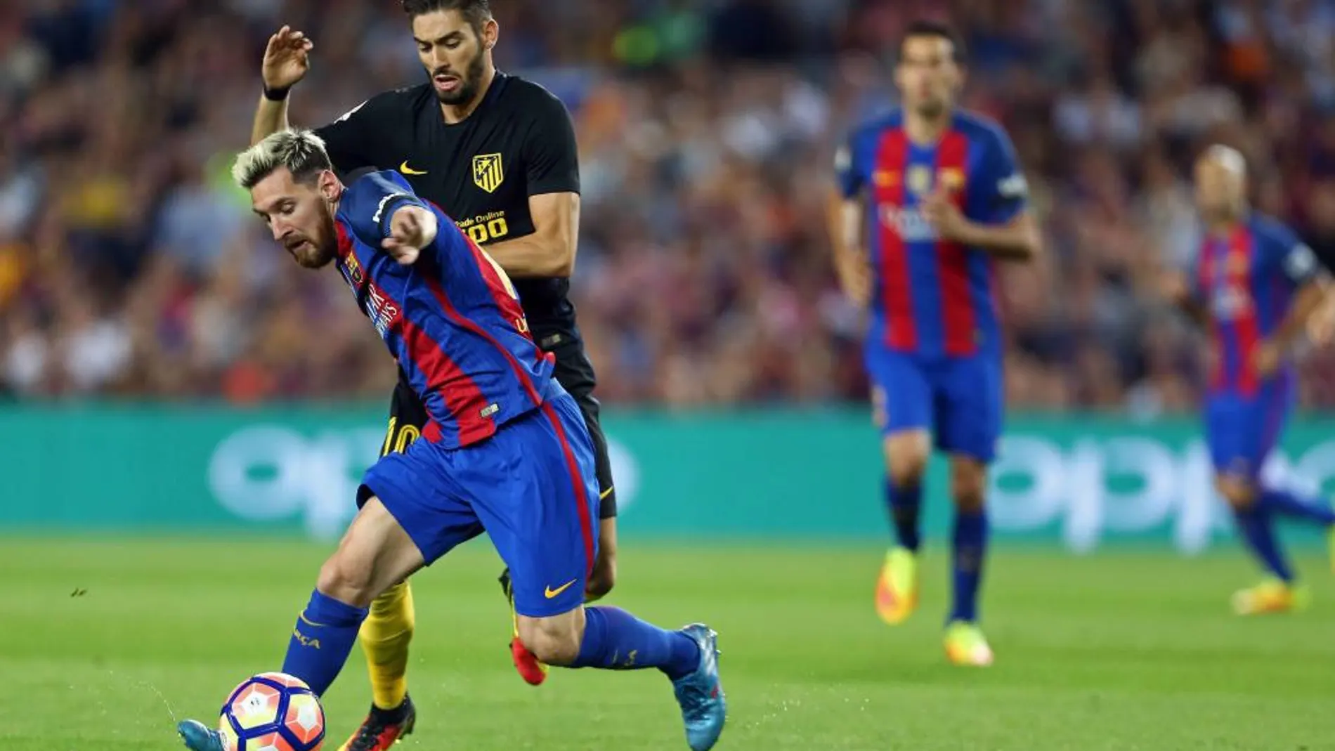 Leo Messi disputa un balón con Yannick Carrasco esta noche en el Camp Nou de Barcelona.