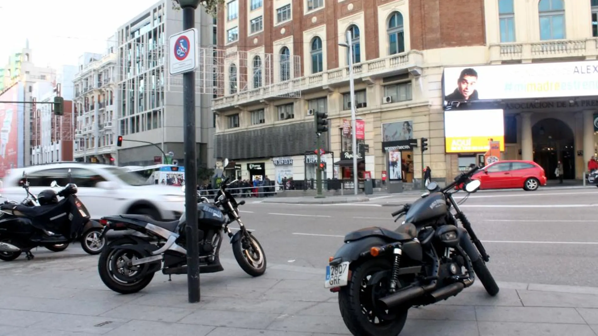 Varias motos estacionadas en una de las aceras de la Gran Vía, bajo la señal de Carmena que lo prohíbe
