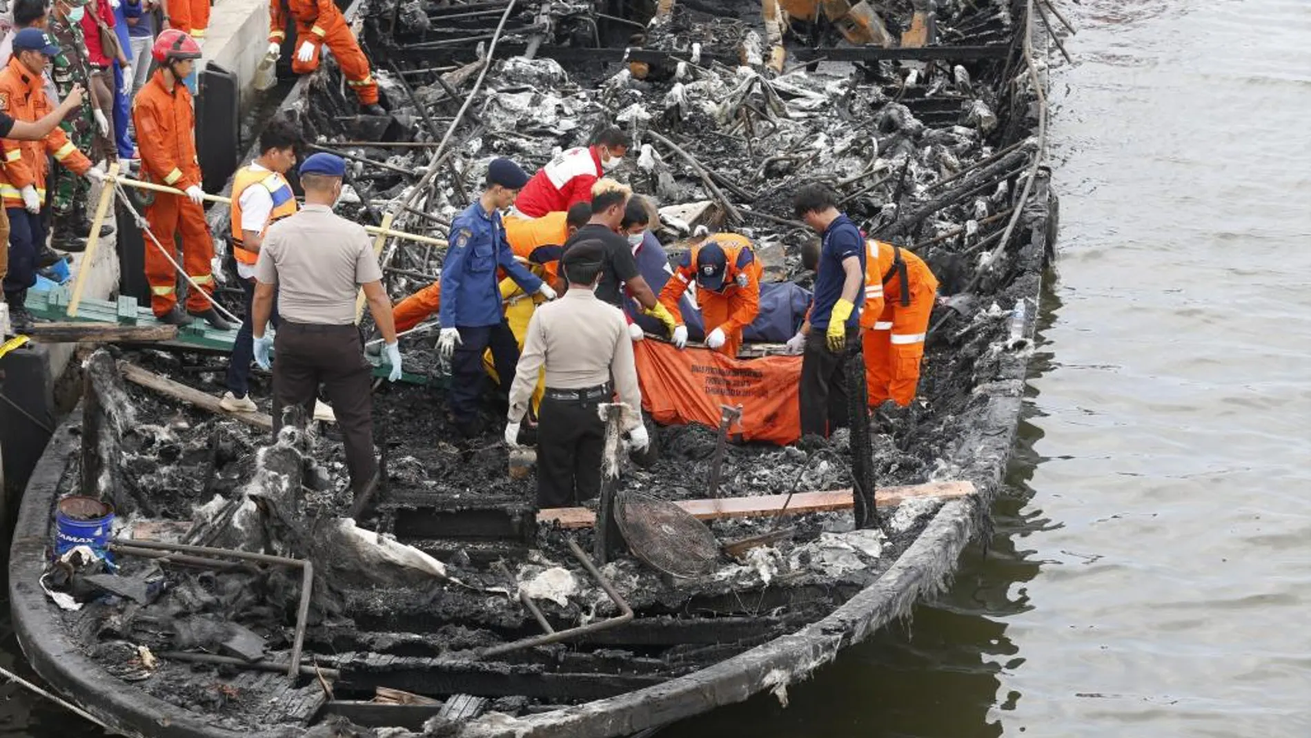 Miembros de los Servicios de Rescate indonesios recuperan los cadáveres de las víctimas de un incendio en una embarcación en el puerto Muara Angke de Yakarta, Indonesia.