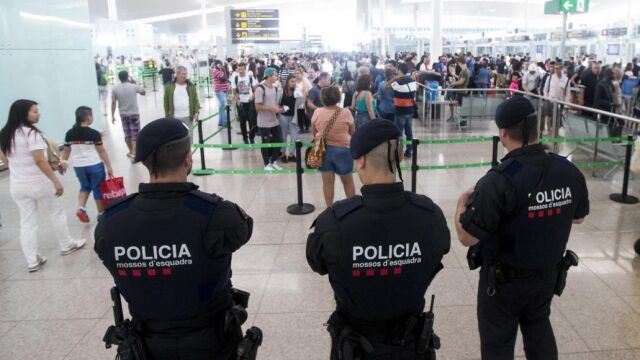 Agentes de los Mossos d'Esquadra controlan de los accesos a las puertas de embarque en el Aeropuerto de El Prat.