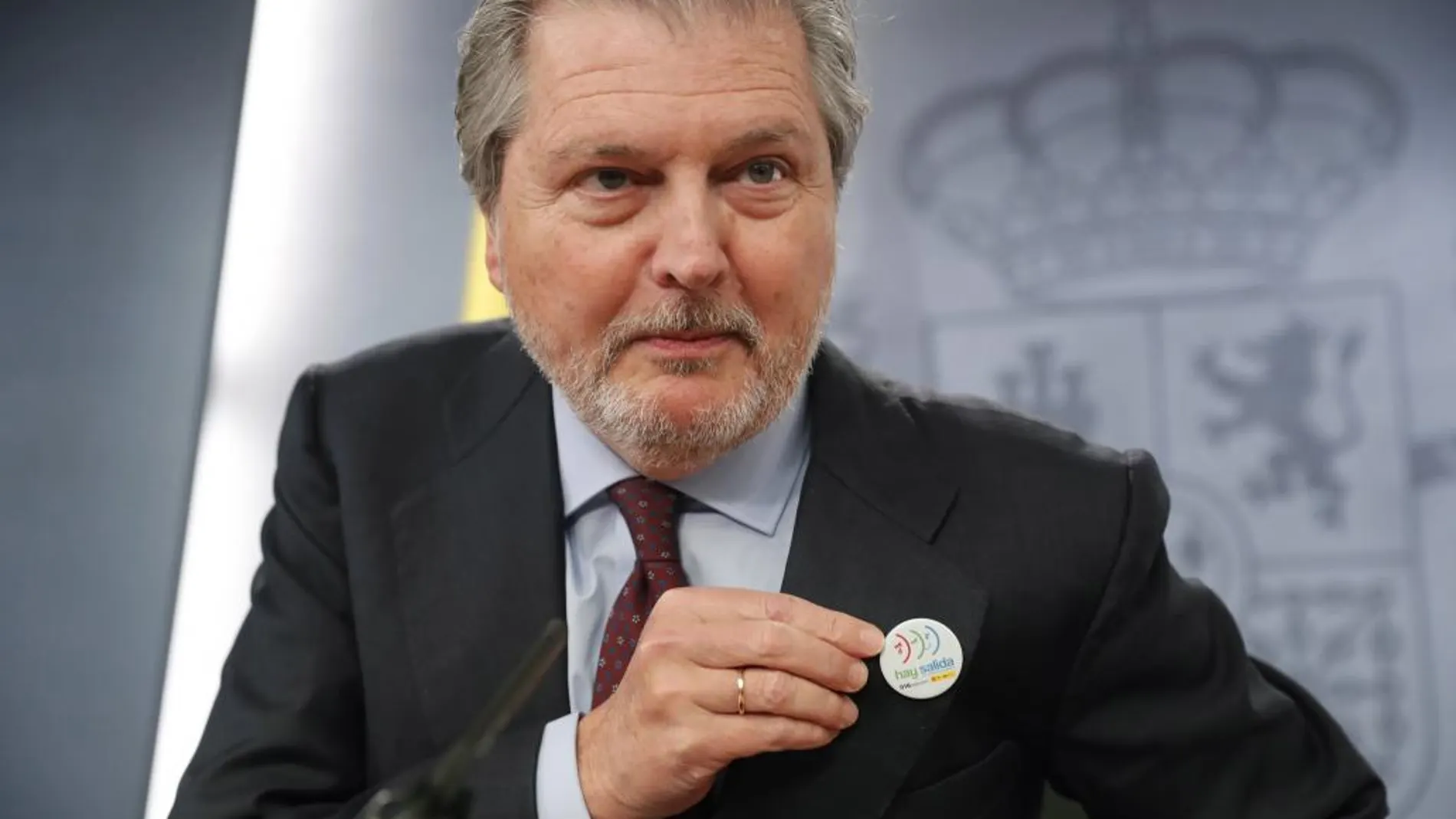 El ministro de Educación y Portavoz del Gobierno,Iñigo Méndez de Vigo, muestra una pin contra la violencia machista, durante la rueda de prensa del Consejo de Ministros