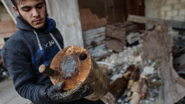 Un hombre carga con el contenedor que supuestamente se utilizó para esparcir gas cloro tras un ataque con cohetes en la zona siria de Al Ghouta oriental, en una foto de archivo