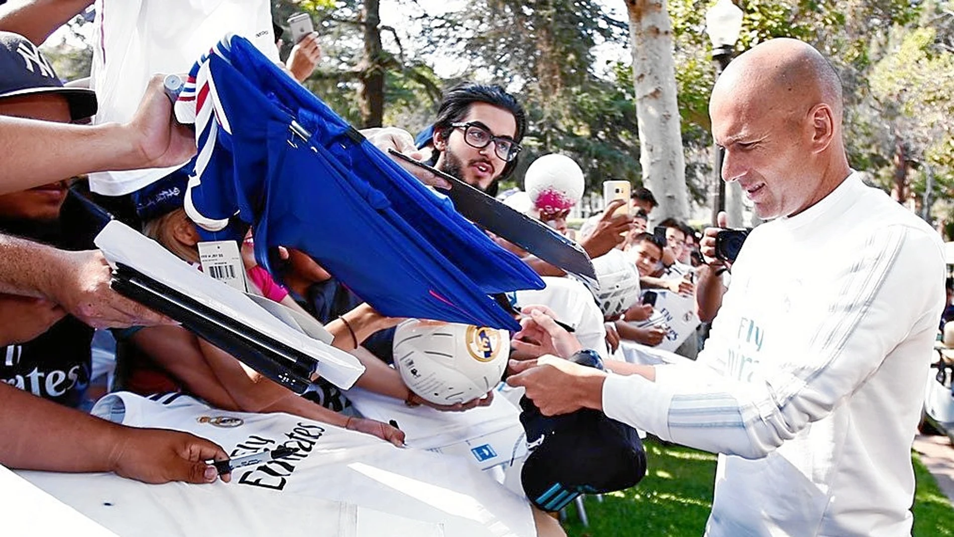 Zidane firma autógrafos en la concentración del Madrid