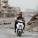 Dos hombres en una moto entre las ruinas de la ciudad de Mosul