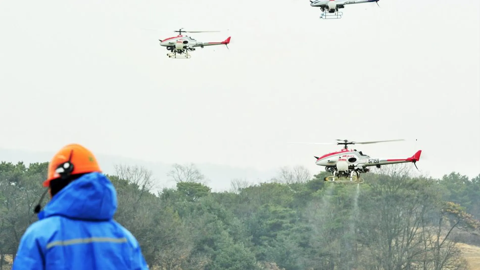 Varios helicópteros teledirigidos rocían productos químicos cerca de un lago en Icheon, al este de Seúl (Corea del Sur)