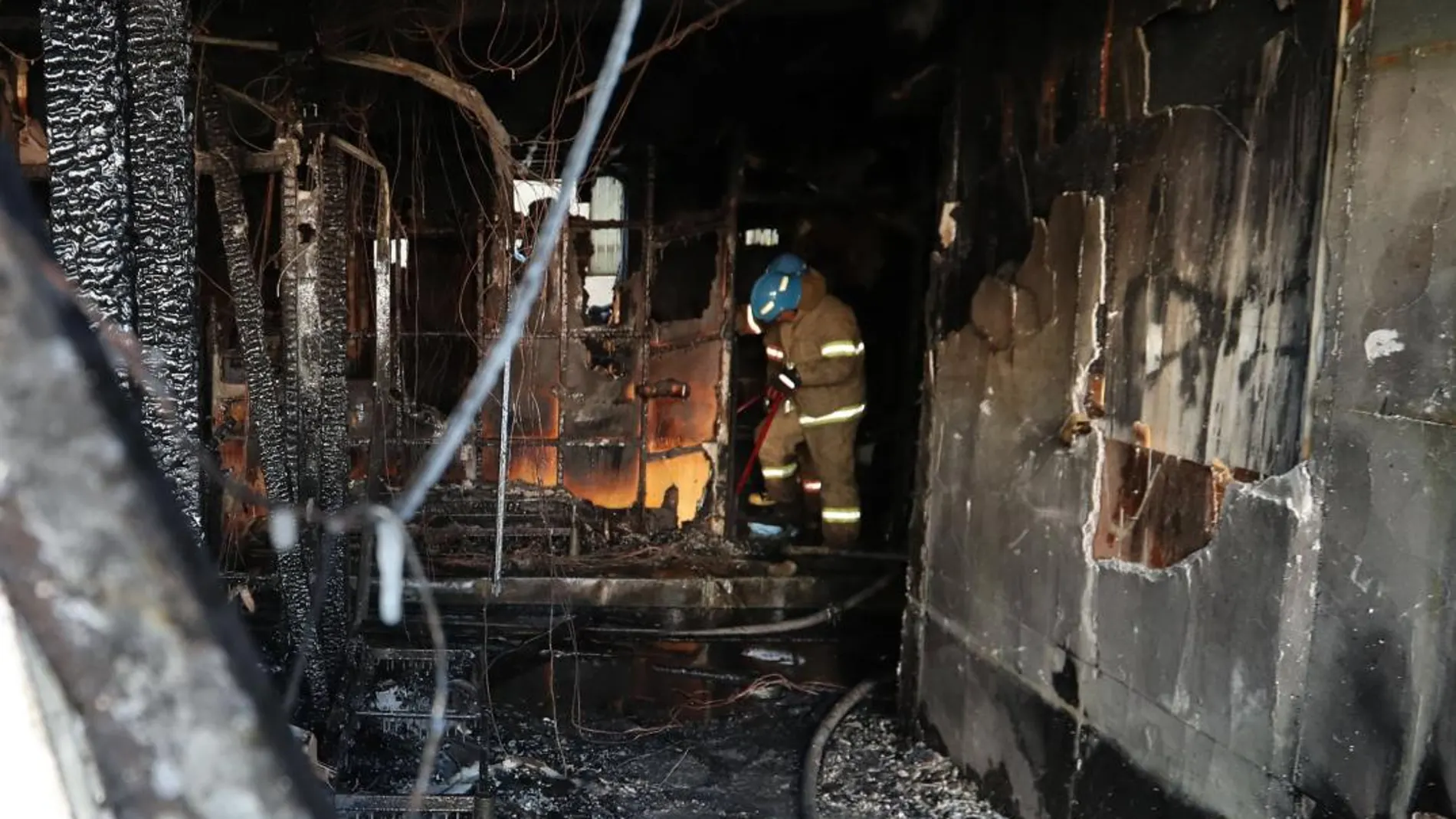 Bomberos apagan los restos del fuego en un cuarto de hospital afectado durante un incendio en Miryang (Corea del Sur)