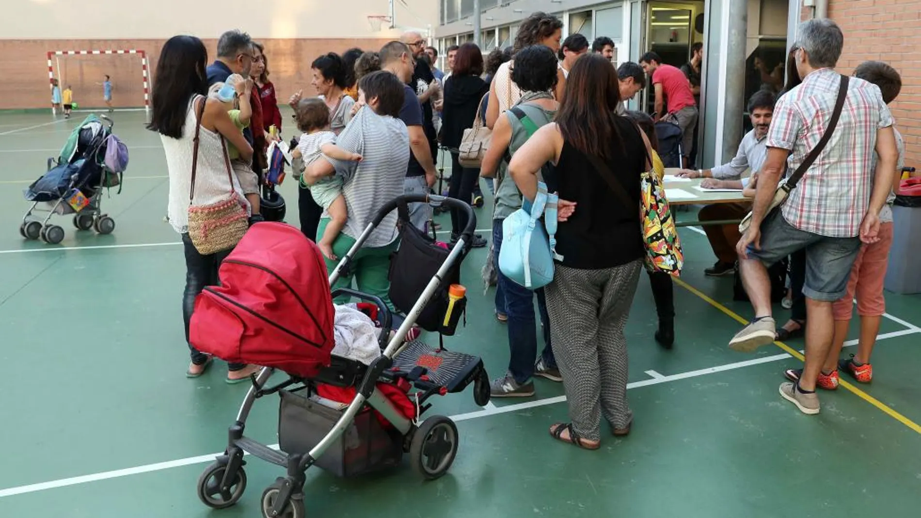 En la imagen, un grupo de padres en el patio de una escuela de Barcelona