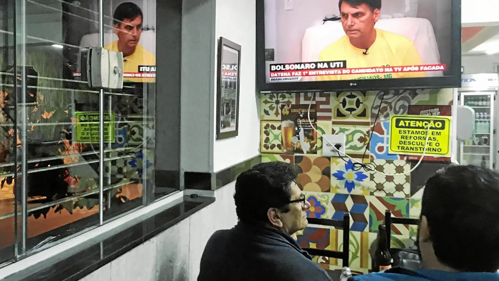 Un grupo de brasileños sigue en directo una entrevista con el candidato presidencial de ultraderecha, Jair Bolsonaro, en un bar de Sao Paulo