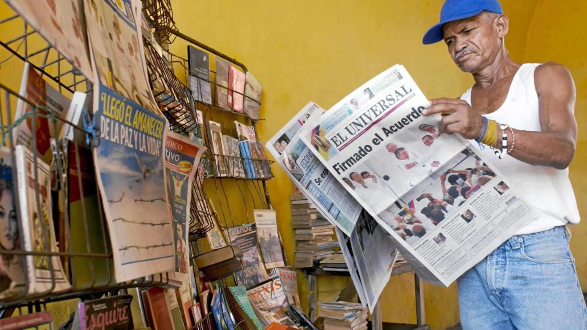 Un colombiano lee el periódico con la portada dedicada a la firma del acuerdo de paz en Cartagena de Indias, ayer