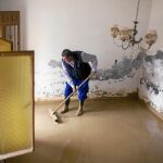 Un vecino trata de sacar toda el agua que ha entrado en su vivienda en Cártama (Málaga)