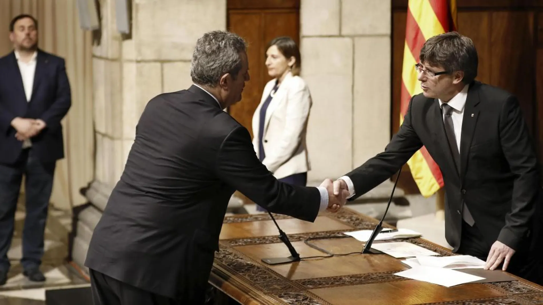 El nuevo conseller de Interior, Joaquim Forn (2i), saluda a Carles Puigdemont (d), durante la toma de posesión de los nuevos cargos esta tarde en el Salón Sant Jordi del Palau de la Generalitat.