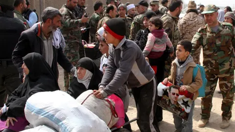 Un niño lleva un retrato del presidente sirio, Bachar al Asad, mientras abandona, junto a cientos de civiles, la zona de Guta Oriental, en la zona rural de Damasco