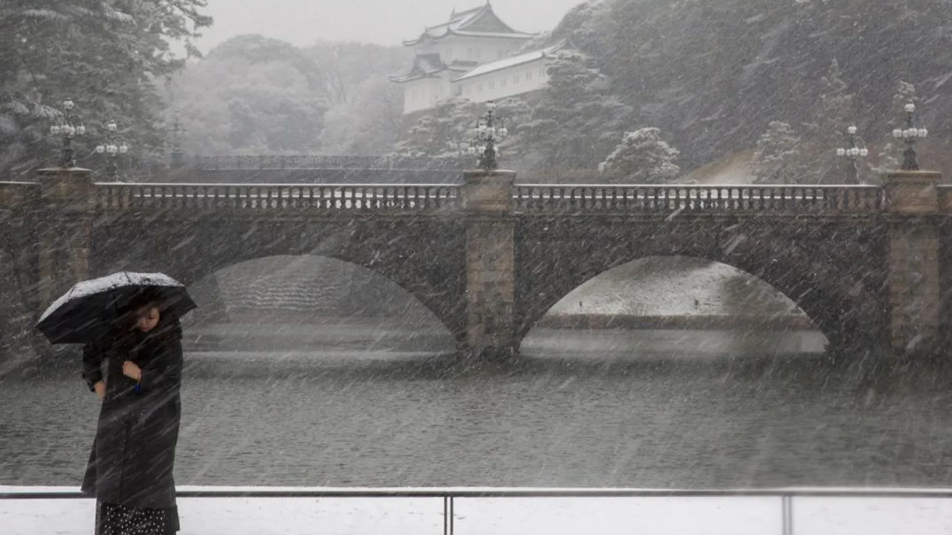 Una mujer se protege con paraguas mientras pasea delante del Palacio Imperial durante una fuerte nevada en Tokio, Japón, hoy