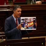 El líder del PPC, Xavier García Albiol, muestra una fotografía de banderas quemadas durante su intervención en la segunda jornada del pleno de la cuestión de confianza planteada por el presidente de la Generalitat, Carles Puigdemont