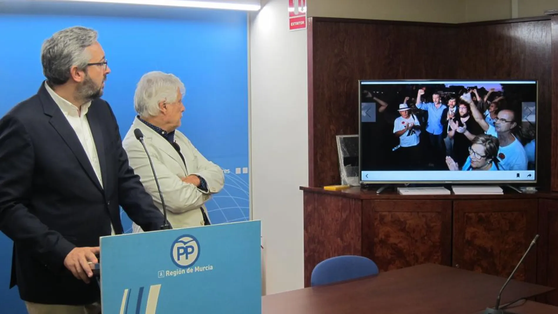 El portavoz del PPRM muestra una fotografía en la que aparece el líder de Podemos