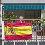 Una vecina de Badía del Vallés tras la bandera de España colocada en su balcón, ayer
