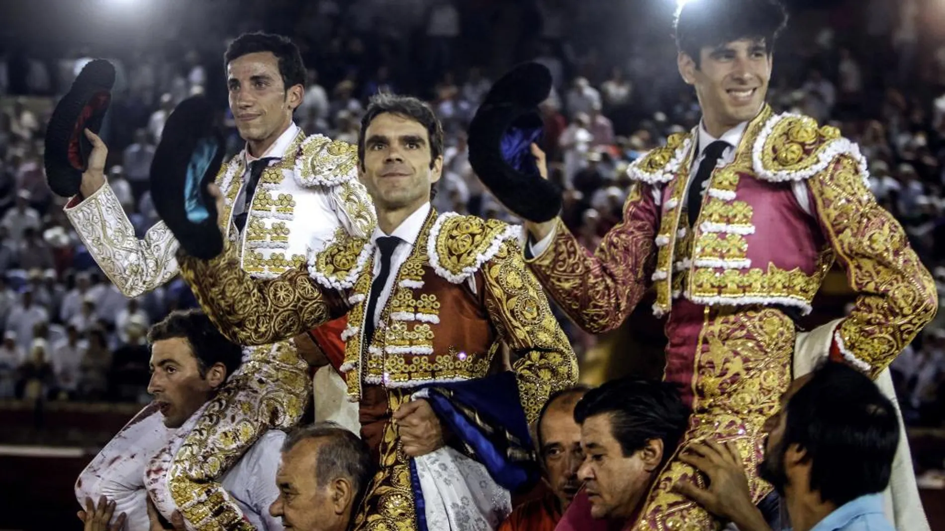 Los diestros José Tomás, David de Miranda (i) y Alberto López Simón (d) salen a hombros tras la corrida de la Feria de las Colombinas celebrada en la plaza de toros de Huelva.