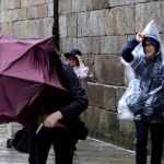 Turistas japoneses luchan por no perder sus paraguas esta mañana en la Plaza del Obradoiro de Santiago de Compostela
