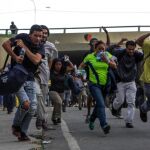 Transeúntes corren para alejarse de los enfrentamientos entre manifestantes opositores y la Guardia Nacional Bolivariana (GNB) durante el "trancazo"de ayer