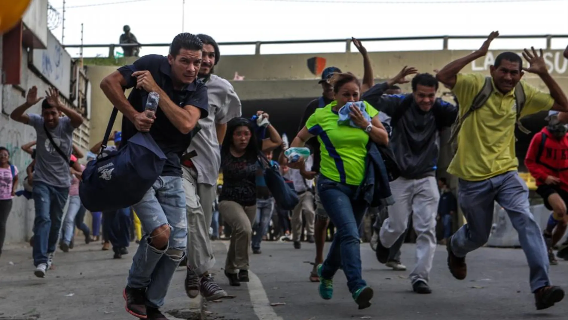 Transeúntes corren para alejarse de los enfrentamientos entre manifestantes opositores y la Guardia Nacional Bolivariana (GNB) durante el "trancazo"de ayer