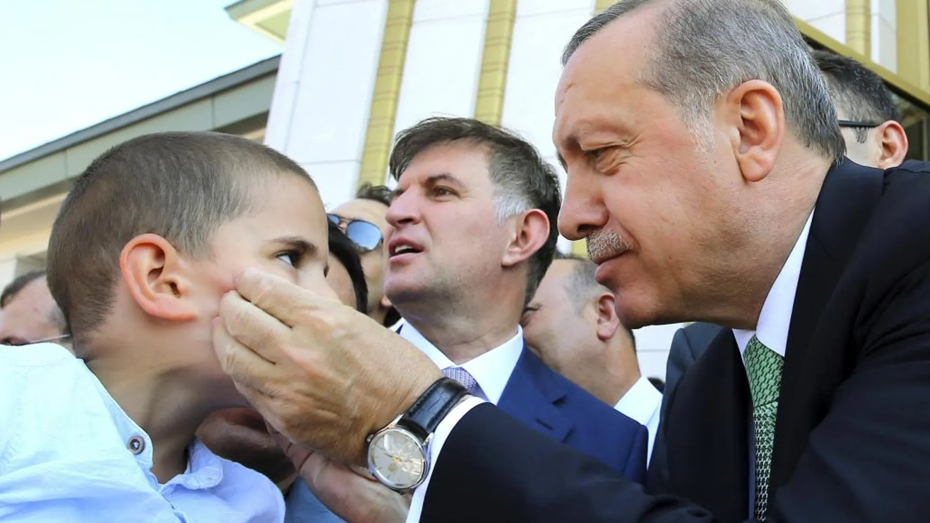 El presidente turco, Tayyip Erdogan, coge la cara de un niño en un acto celebrado ayer