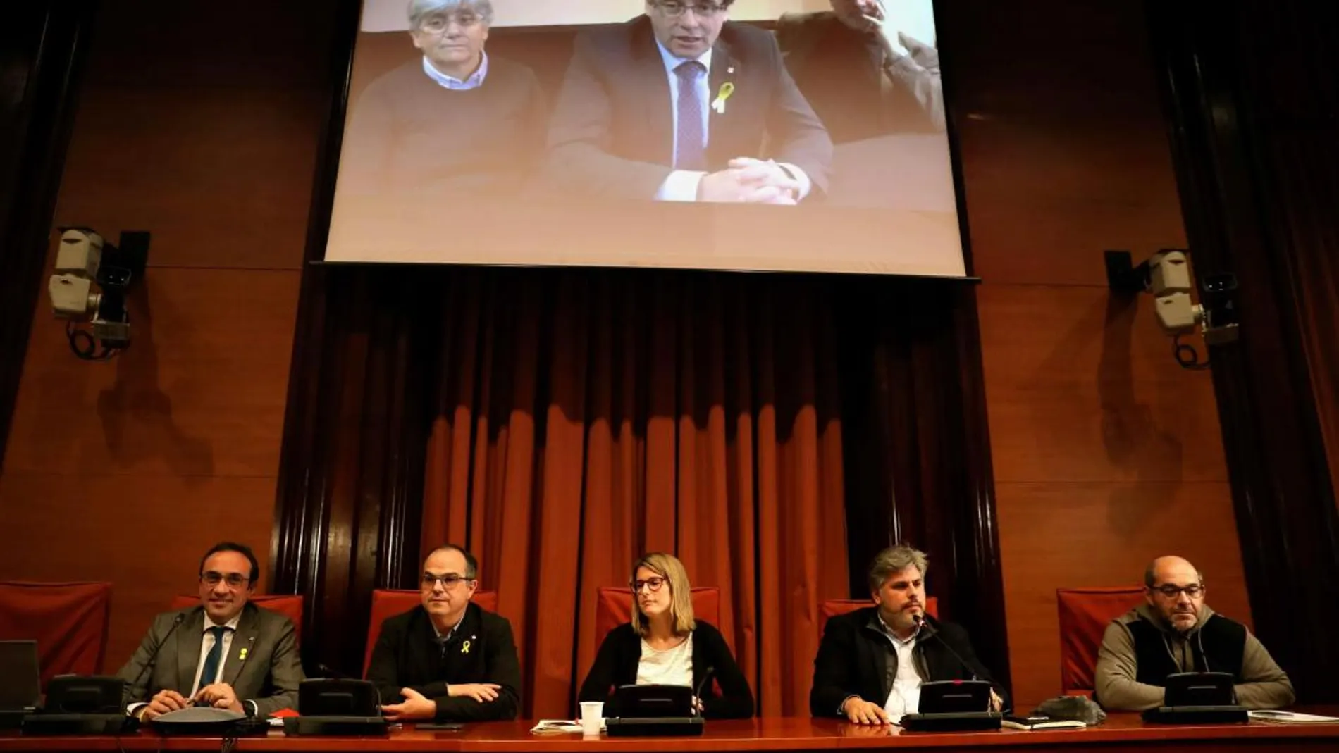 Los diputados electos Carles Puigdemont (c), Clara Pontasí (i) y Lluís Puig (d), participaron telemáticamente desde Bruselas en la reunión celebrada en el Parlament