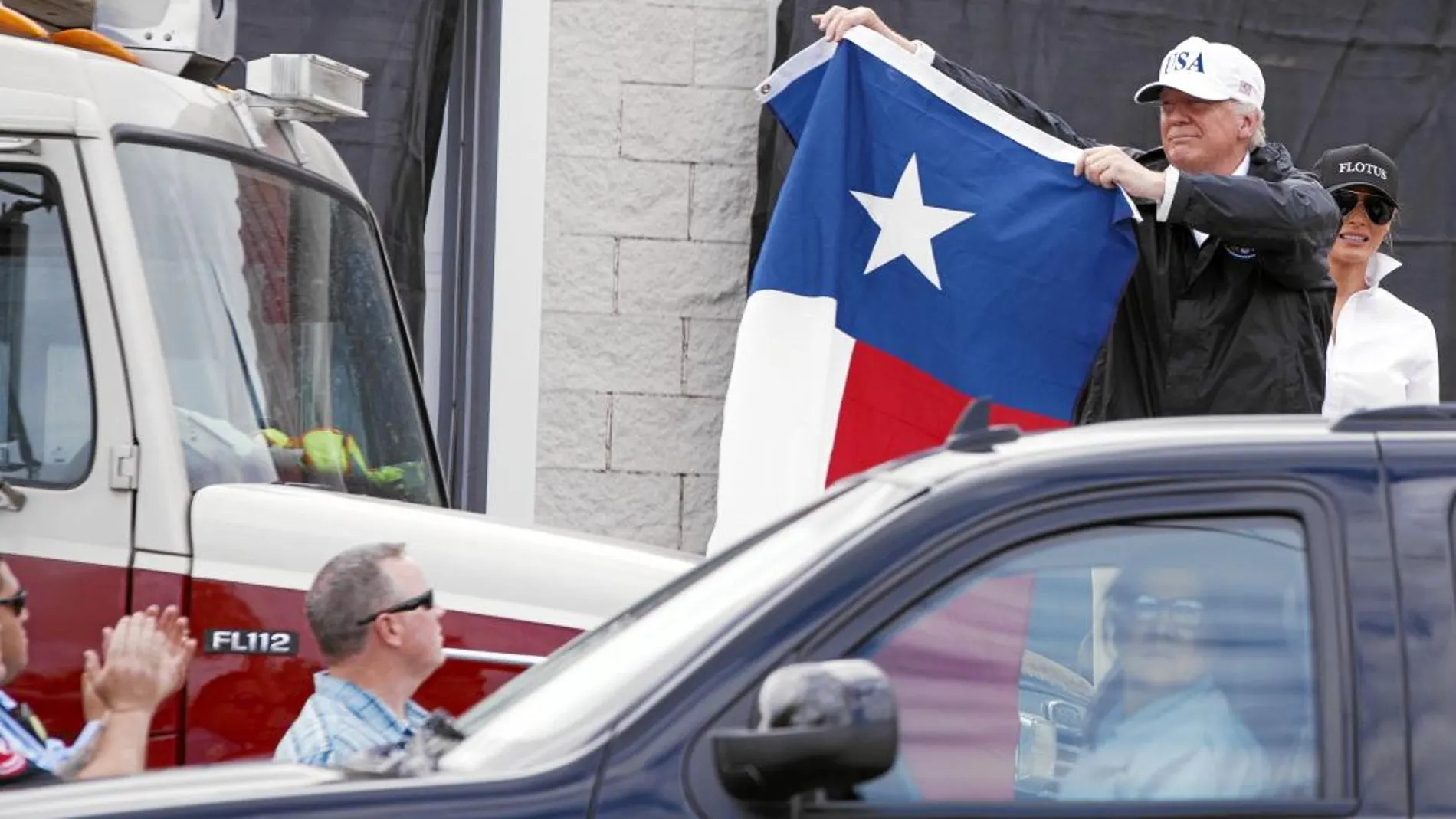 Donald Trump muestra una bandera de Texas después de hablar con sus seguidores, ayer, en una de las zonas afectadas por el huracán