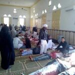 Varias personas permanecen junto a cuerpos sin vida en el interior una mezquita contra la que se ha perpetrado un ataque, en la ciudad de Al Arish