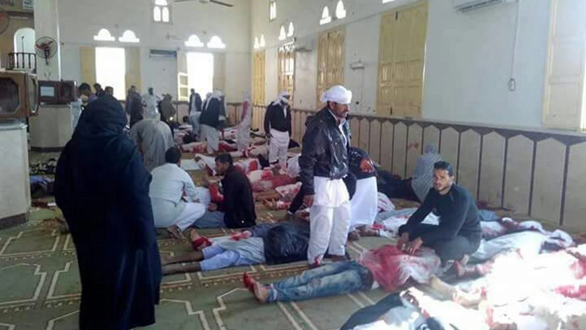 Varias personas permanecen junto a cuerpos sin vida en el interior una mezquita contra la que se ha perpetrado un ataque, en la ciudad de Al Arish