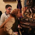 Una mujer besa el pie al Nazareno observada por su nieto