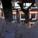 El reflejo de una fachada poblada de banderas nacionales y catalanas en una calle de Madrid