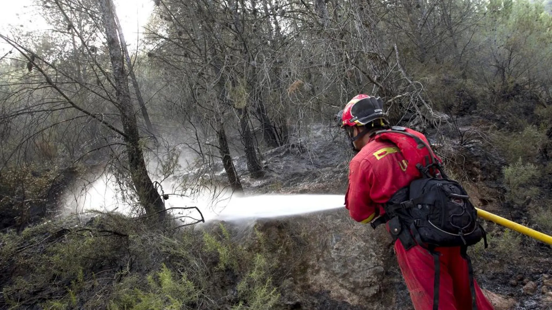Un miembro de la UME refresca zonas quemadas en el perímetro del incendio de la Sierra de Espadán