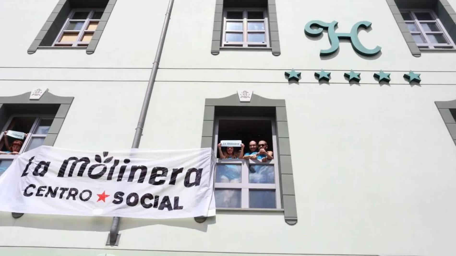 Vecinos que han ocupado el antiguo hotel Marqués de la Ensenada de Valladolid, se asoman a una de las ventanas para reclamar un centro social