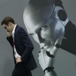Un visitante al Mobile World Congress (MWC) de Barcelona habla por teléfono mientras pasa por un stand de inteligencia artificial