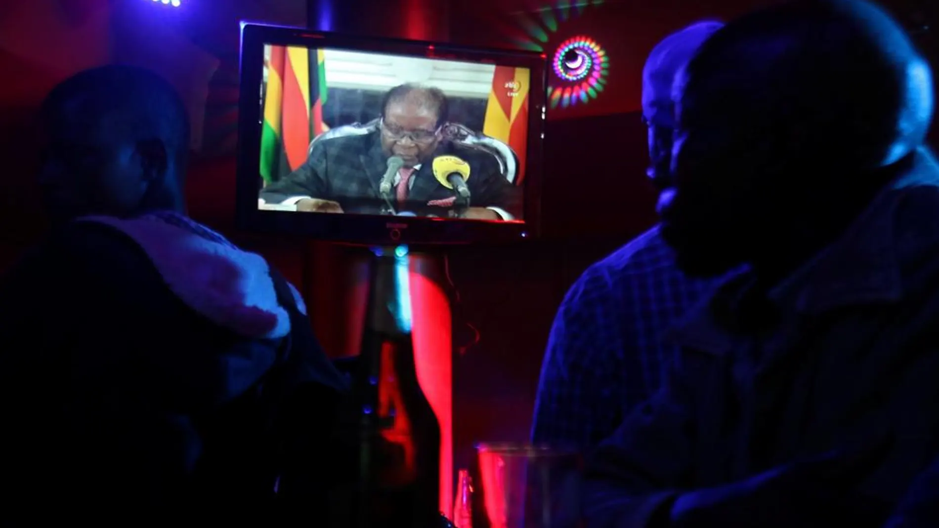 Varias personas siguen por televisión el mensaje de Mugabe