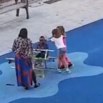 Momento en el que dos niñas se acercan al niño negro y le golpean en la cabeza
