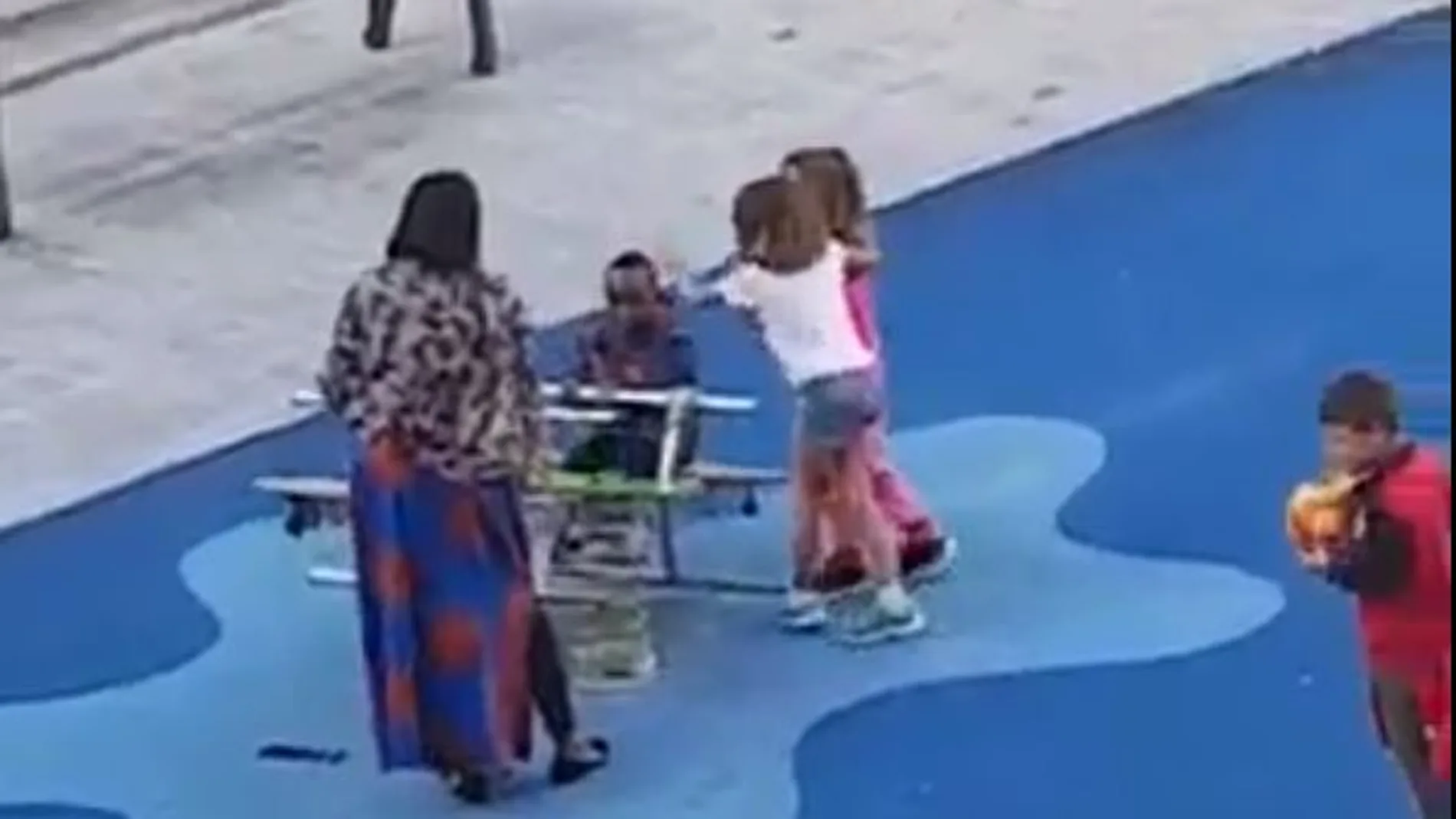 Momento en el que dos niñas se acercan al niño negro y le golpean en la cabeza