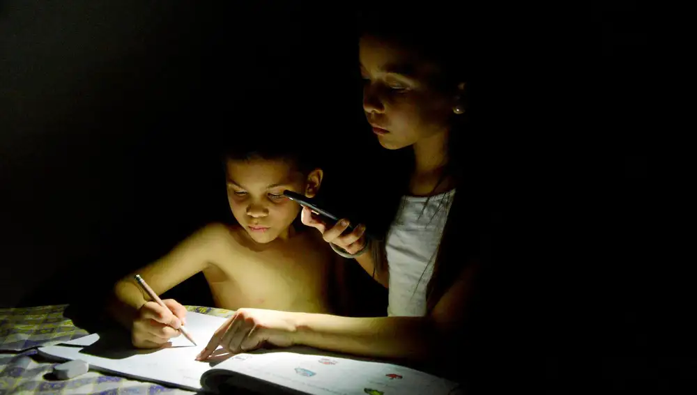 Dos niños estudian con la luz de móvil durante un apagón en Maracaibo (Venezuela)