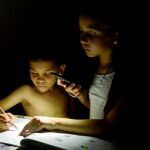 Dos niños estudian con la luz de móvil durante un apagón en Maracaibo (Venezuela)