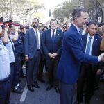 El Rey Don Felipe saluda a un miembro de los Mossos d’Esquadra en presencia de otros agentes y ante la mirada del presidente del Gobierno, Mariano Rajoy, ayer en Barcelona
