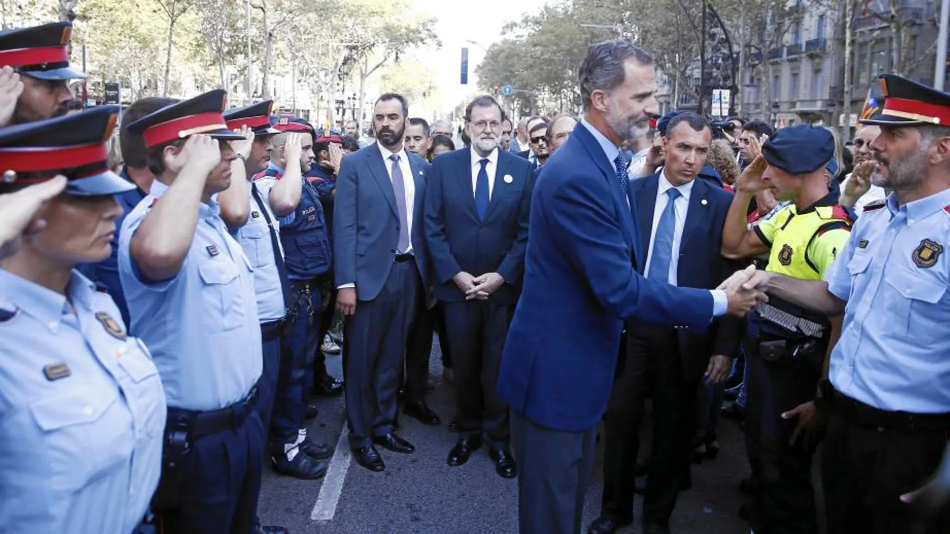 El Rey Don Felipe saluda a un miembro de los Mossos d’Esquadra en presencia de otros agentes y ante la mirada del presidente del Gobierno, Mariano Rajoy, ayer en Barcelona