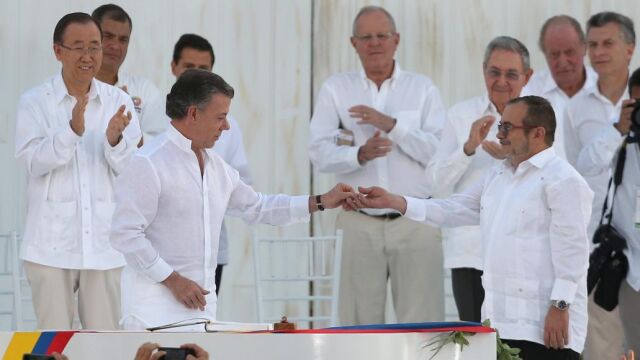 Juan Manuel Santos entrega un pin de la paz a Timochenko, el líder de las FARC