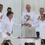 Juan Manuel Santos entrega un pin de la paz a Timochenko, el líder de las FARC
