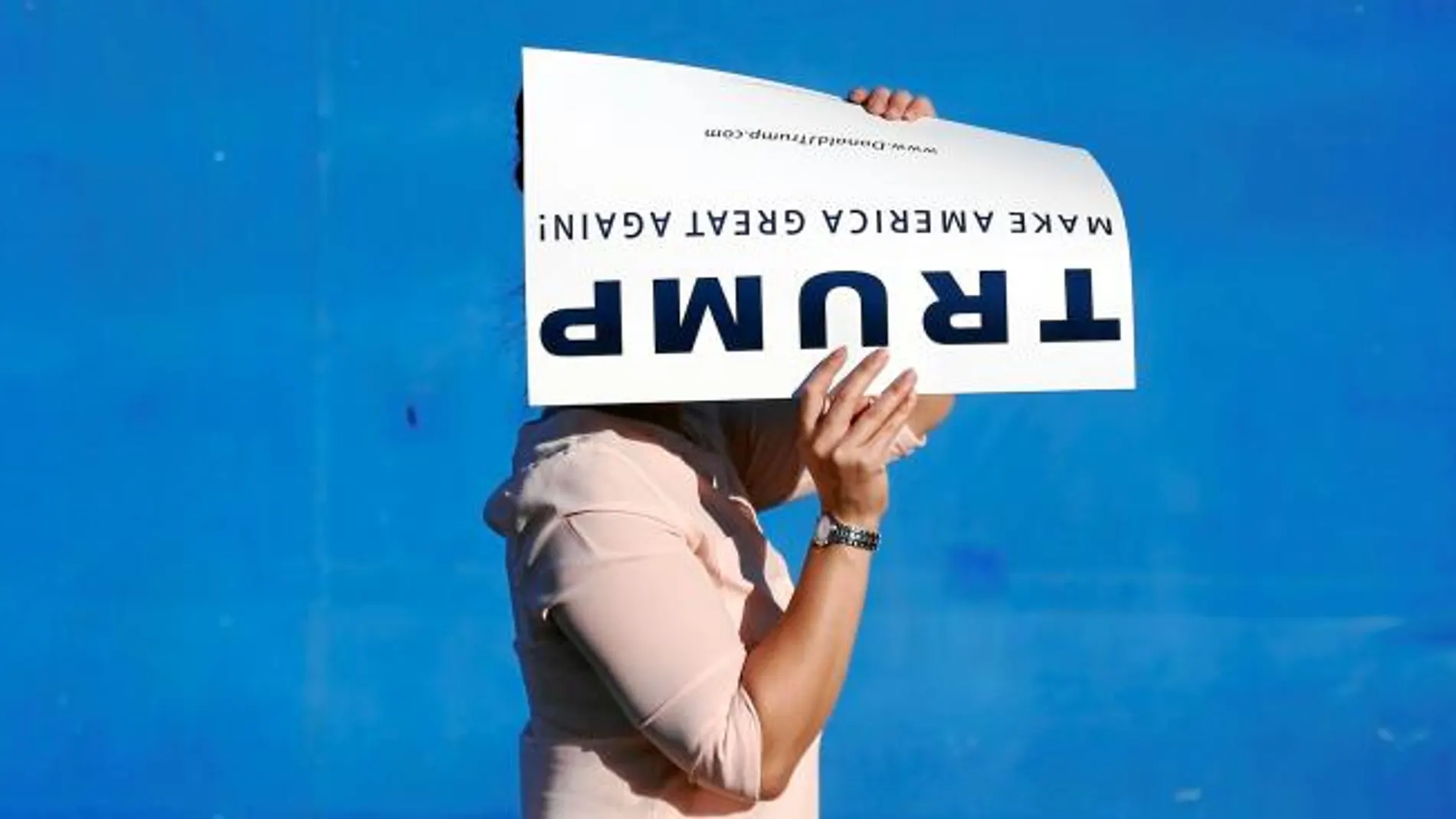 Una mujer con un cartel de la campaña de Donald Trump en la ciudad de San José, en California
