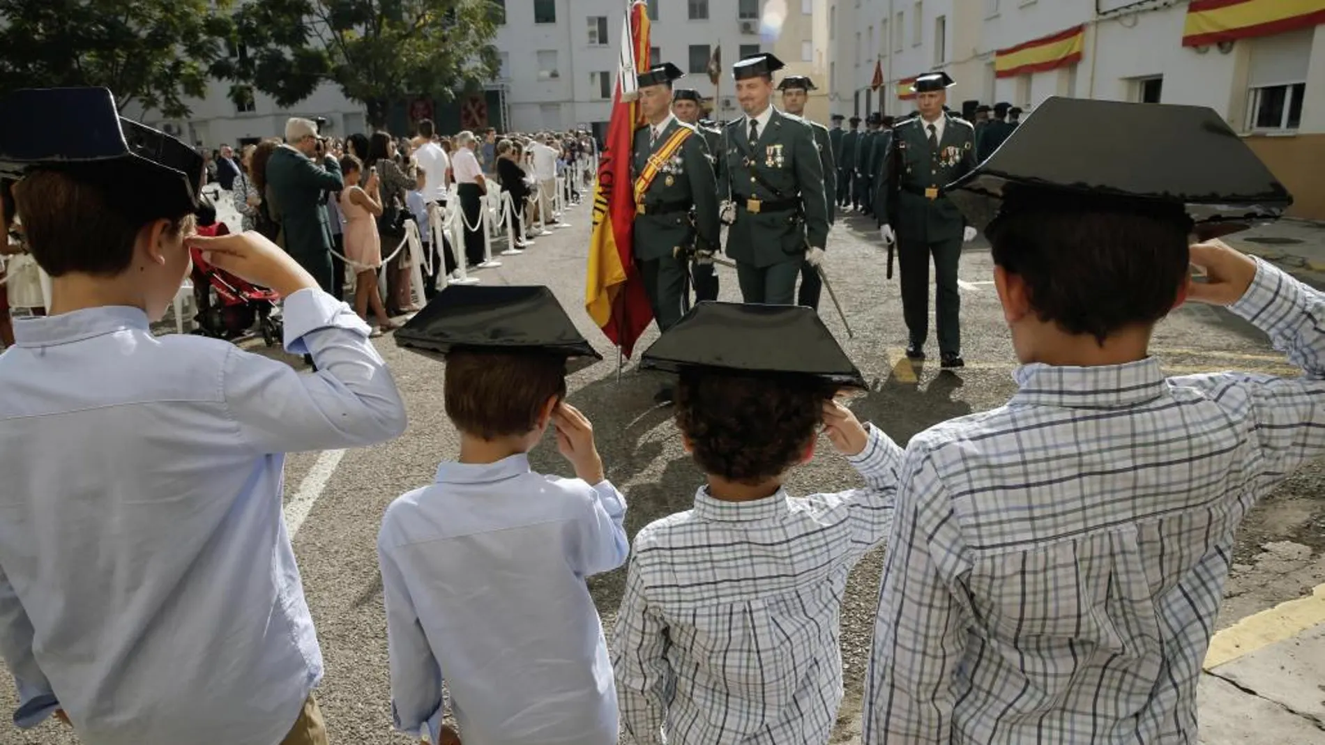 Cuatro niños saludan el paso de los guardias civiles en la Comandancia de Valencia durante los actos de la Virgen del Pilar, patrona del Cuerpo.