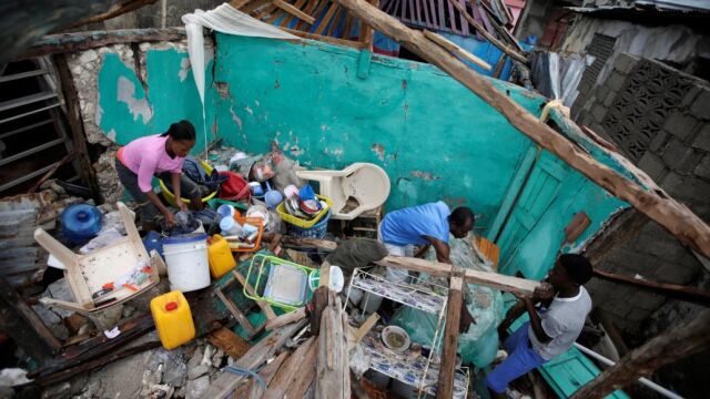 Una familia trata de rescatar algunas de sus pertenencias de su casa destruida por el huracán