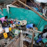 Una familia trata de rescatar algunas de sus pertenencias de su casa destruida por el huracán