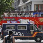Un autobús turístico pasa ante un furgón de la Policía Nacional estacionado en una calle peatonal del centro de Valencia.