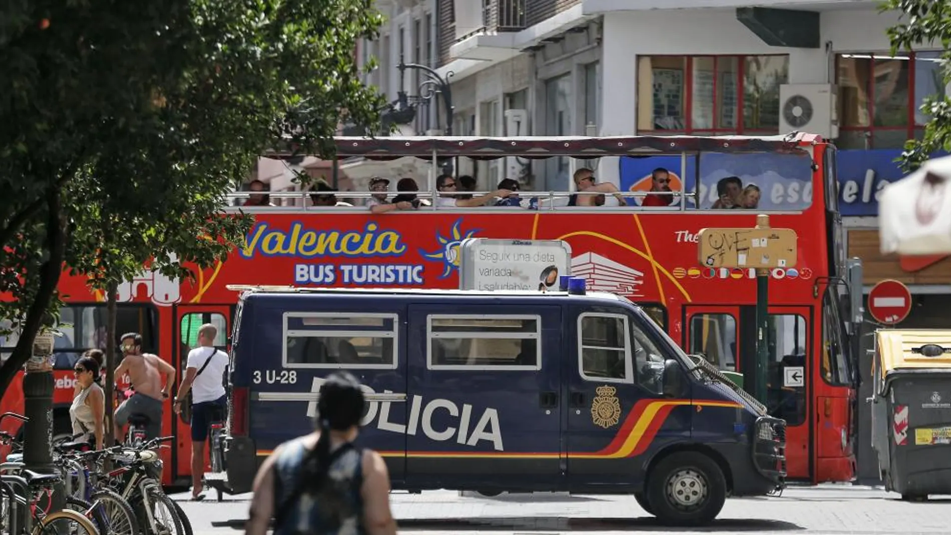 Un autobús turístico pasa ante un furgón de la Policía Nacional estacionado en una calle peatonal del centro de Valencia.