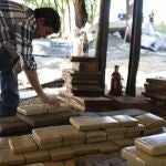 Un hombre junto a varias placas de marihuana prensada, incautada por agentes de la Secretaría Antidroga de Paraguay (Senad).